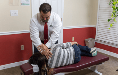 Spartanburg chiropractor pressing on woman's neck while she is laying down.