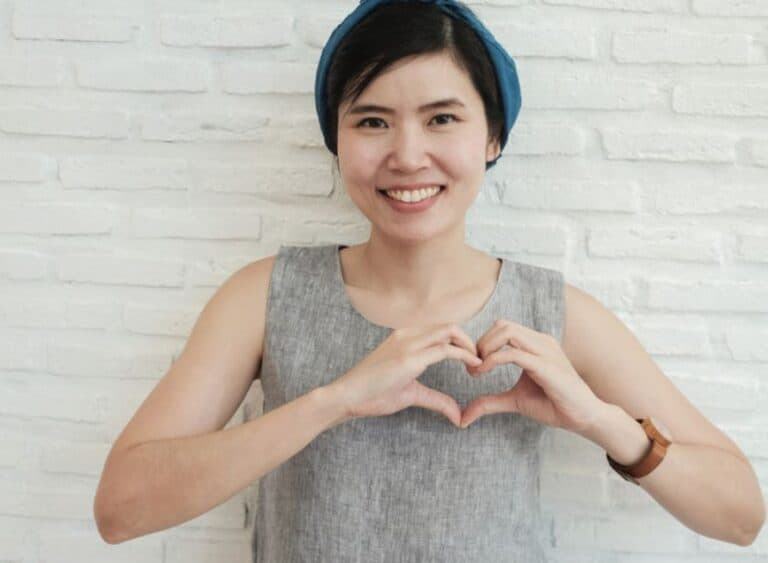 Healthy woman smiling and posing with sign language for a heart